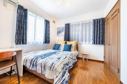 a bedroom with a bed and a desk and windows at ナインヴィラ九十九里 in Kujukuri