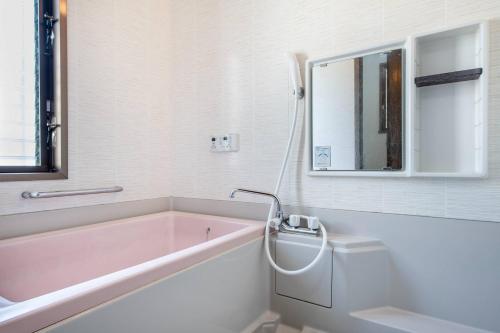 a bathroom with a pink bath tub and a mirror at ナインヴィラ九十九里 in Kujukuri
