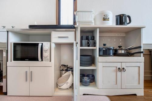a white cabinet with a microwave and some dishes at ナインヴィラ九十九里 in Kujukuri