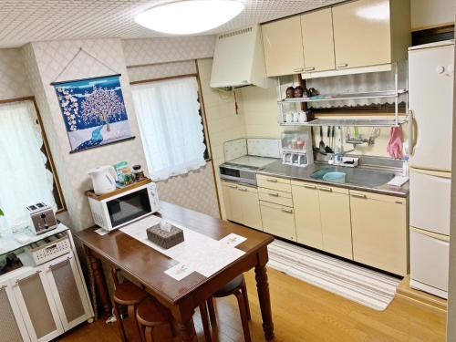 eine Küche mit einem Tisch, einer Mikrowelle und einem Herd in der Unterkunft Reina Building 4F / Vacation STAY 61776 in Tokushima