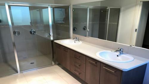 La salle de bains est pourvue de 2 lavabos et d'une douche. dans l'établissement 24 Kangaroo Run Tura Beach, à Tura Beach