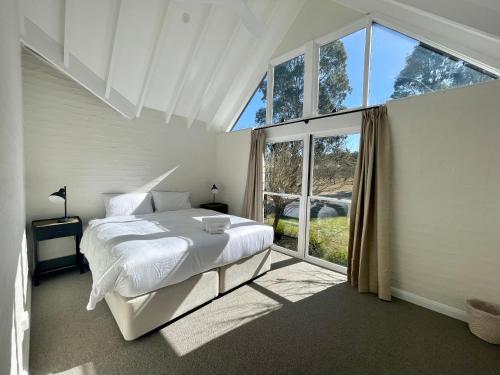 a bedroom with a white bed and a large window at Talga Grove in Rothbury