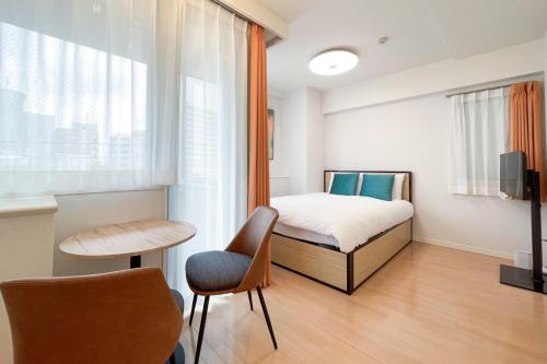 een slaapkamer met een bed, een tafel en een stoel bij Luce Takanawa in Tokyo