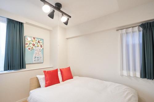a bedroom with a white bed with red pillows at Luce Takanawa in Tokyo