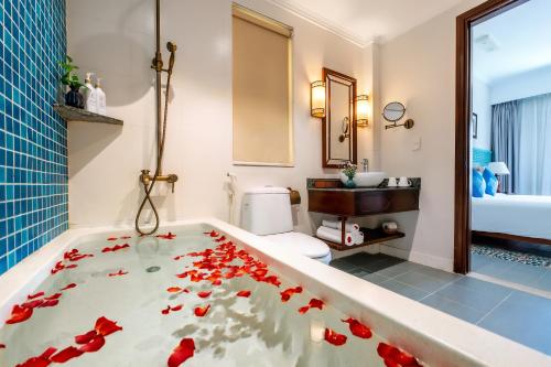 a bathroom with a tub with red flowers in it at Lantana Boutique Hoi An Hotel in Hoi An