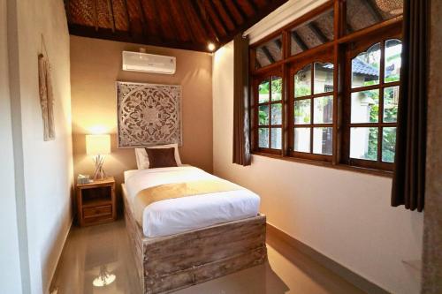 a bedroom with a bed in a room with windows at Villa Santai in Seminyak