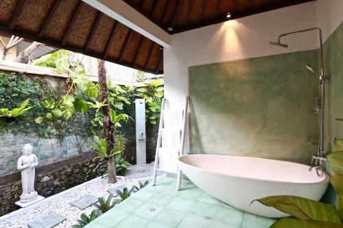 a bath tub in a bathroom with a garden at Villa Santai in Seminyak