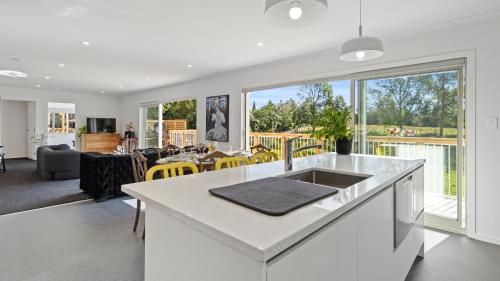 a kitchen and living room with a large window at The Whitehouse - Lepperton Holiday Home in New Plymouth