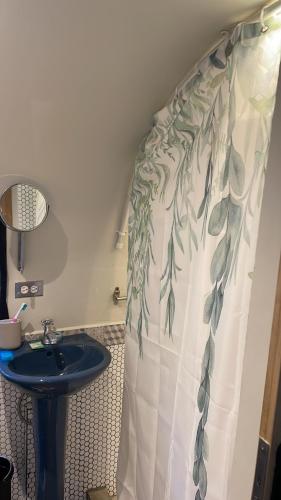 a bathroom with a sink and a shower curtain with leaves at Sal & Turq in Roatan