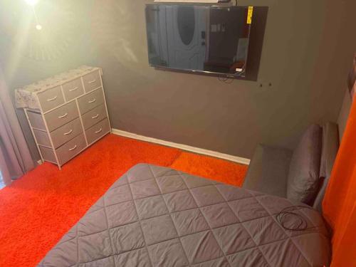 a bedroom with a bed and a tv on the wall at Backyard Guesthouse in Miami Gardens