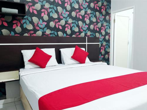 een slaapkamer met een groot wit bed met rode kussens bij Lucky Inn & Cafe in Patjinongong