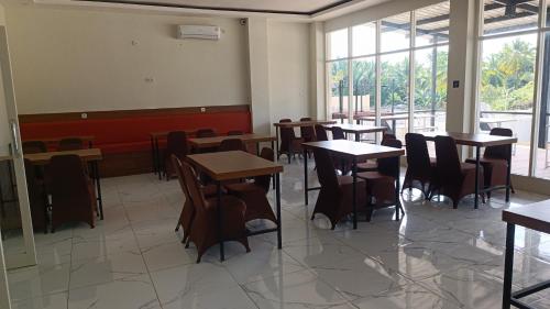 uma sala de jantar com mesas, cadeiras e janelas em Hotel Apex Dobo em Dobo