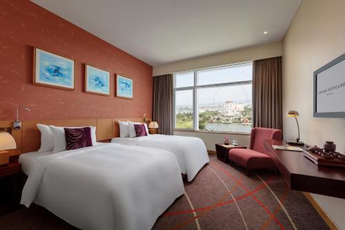 a hotel room with two beds and a window at Grand Mercure Danang in Da Nang