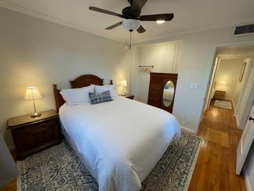 a bedroom with a white bed and a ceiling fan at The Corner Cottage in El Centro