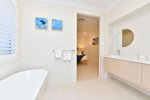 Baño blanco con lavabo y espejo en Coolabah House - Tranquil Haven in Nulkaba en Nulkaba