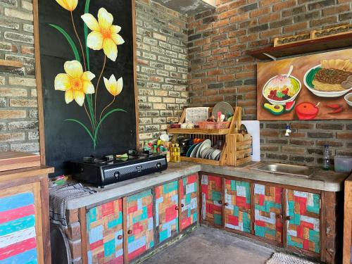 a kitchen with a counter and a painting of flowers on the wall at Sirya Farm House in Meliling