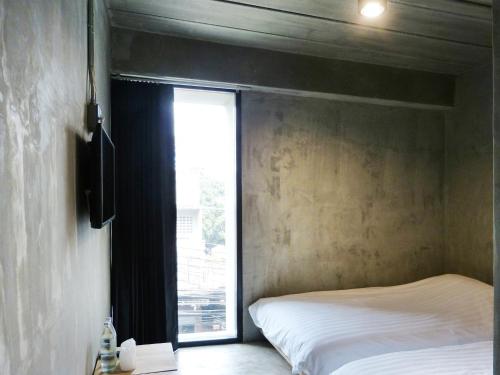 sypialnia z łóżkiem i dużym oknem w obiekcie B+Arch House / Hotel&Cafe w mieście Chiang Mai