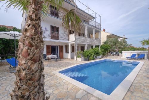 een villa met een palmboom en een zwembad bij Apartments Priko in Stari Grad