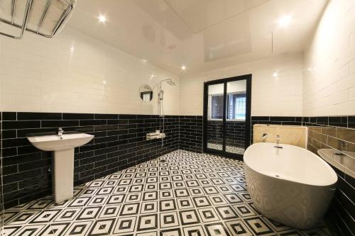 a bathroom with a tub and a sink at Almond Hotel Gupo Station in Busan