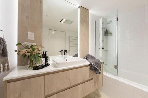 een badkamer met een wastafel, een douche en een bad bij Accommodate Canberra - Metropolitan 70 in Canberra