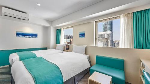 a hotel room with two beds and a window at DEL style Osaka Shin Umeda by Daiwa Roynet Hotel in Osaka