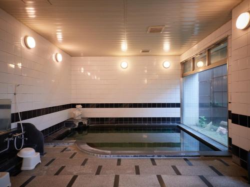 Tabist Onsen Hotel Toyo في Fuefuki: مسبح في حمام مع مرحاض