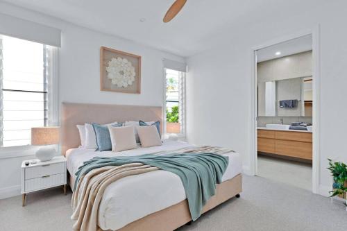 a white bedroom with a large bed and a kitchen at LEO2-SOPHISTICATED, BEACH HOLIDAY HOME in Alexandra Headland