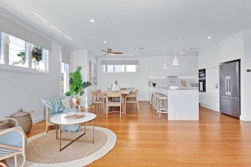 a white living room with a table and a kitchen at LEO2-SOPHISTICATED, BEACH HOLIDAY HOME in Alexandra Headland