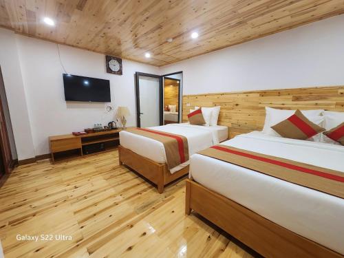 a hotel room with two beds and a television at SaPa Retreat Condotel in Sa Pa