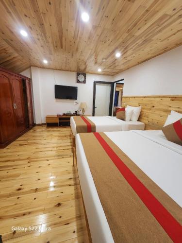 a hotel room with two beds and a flat screen tv at SaPa Retreat Condotel in Sa Pa