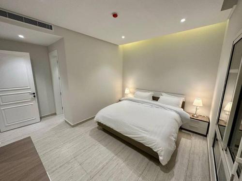 a white bedroom with a bed and a door at AlYasmin, S&M Luxury Apartment in Riyadh