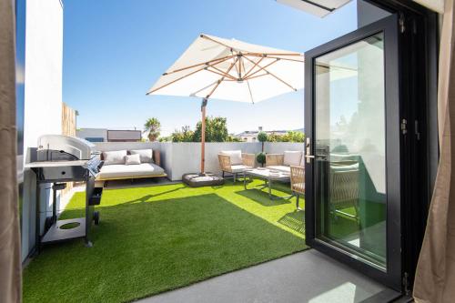 un patio con sombrilla y césped verde en Regency Modern Apartments en Los Ángeles