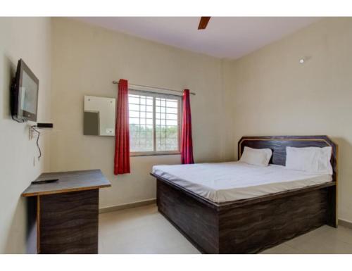 a bedroom with a bed and a window with red curtains at Vedanta Hotel, Bareilly in Bareilly