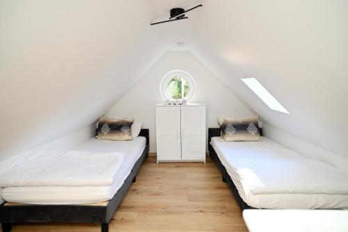 two beds in a attic room with a window at Ferienwohnung & Aparts am Schloss Park in Essen