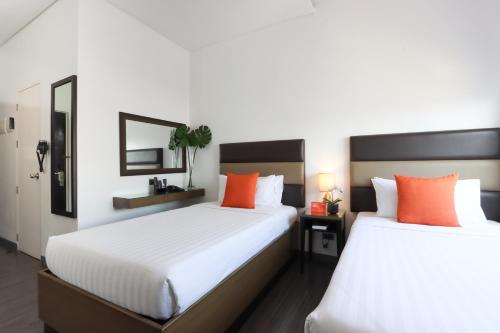 two beds in a room with white and orange pillows at Privato Makati in Manila