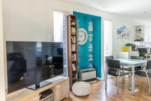 a dining room with a large television and a dining table at Coral Cottage in Berrara