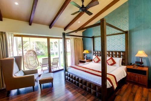 a bedroom with a bed and a chair and windows at MGM Beach Resorts East Coast Road in Chennai