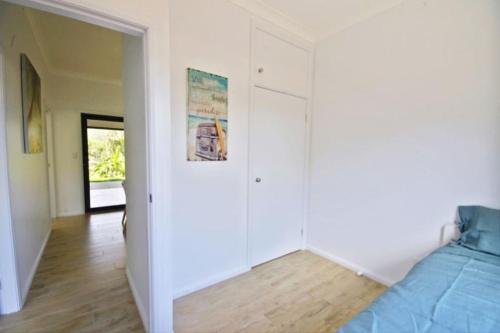 a bedroom with white walls and a bed and a hallway at Hilltop Retreat - best of both worlds: Beach/farm in Pillar Valley