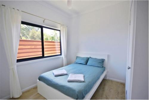 een kleine slaapkamer met een bed en een raam bij Hilltop Retreat - best of both worlds: Beach/farm in Pillar Valley