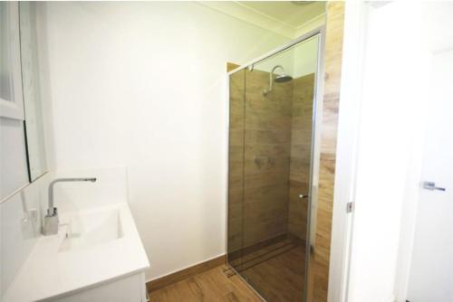 een badkamer met een douche, een wastafel en een spiegel bij Hilltop Retreat - best of both worlds: Beach/farm in Pillar Valley