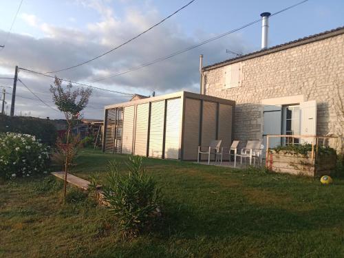 a building with a storage shed next to a yard at Le Logis du Bouil in Champagne