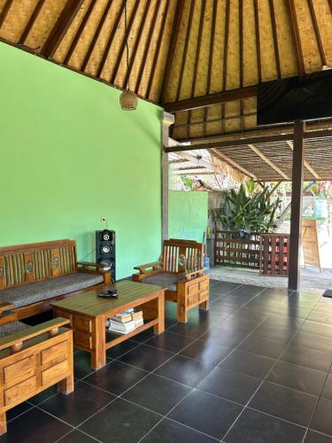 a living room with wooden furniture and a green wall at Island Garden Huts Lembongan in Nusa Lembongan