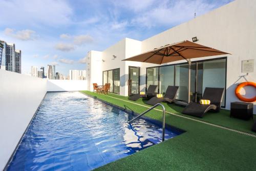 a pool with chairs and an umbrella on a building at Privato Makati in Manila