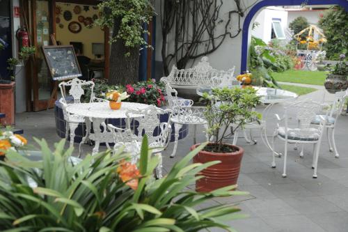 a patio with white tables and chairs and plants at Hotel Casa Gonzalez in Mexico City