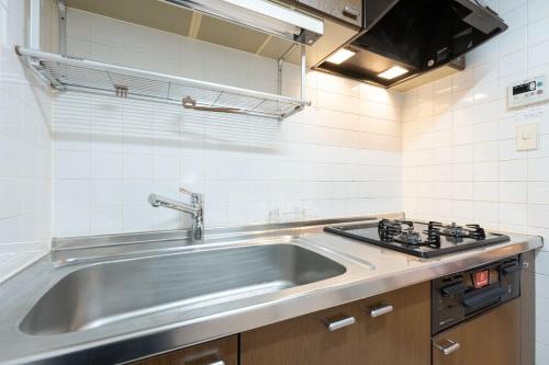 a kitchen with a stainless steel sink and a stove at Raiwa Mansion Minami Azabu in Tokyo