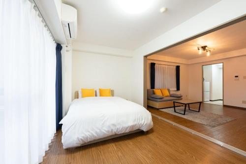 a bedroom with a white bed and a living room at Raiwa Mansion Minami Azabu in Tokyo