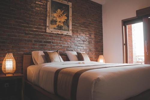 a bedroom with a large bed with a brick wall at Govardan Home stay in Canggu