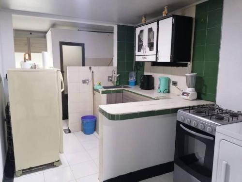 a kitchen with white appliances and green tiles at Disfruta tu estancia en Pereira! in Pereira