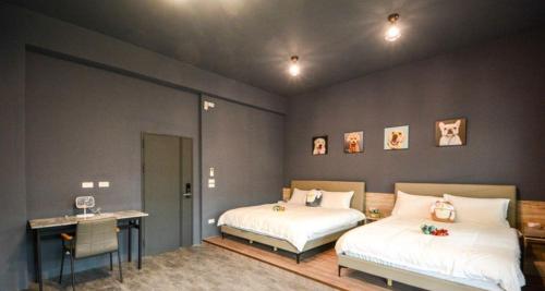 a bedroom with two beds and a table and a desk at 快樂狗寵物民宿--證號2598 in Hualien City