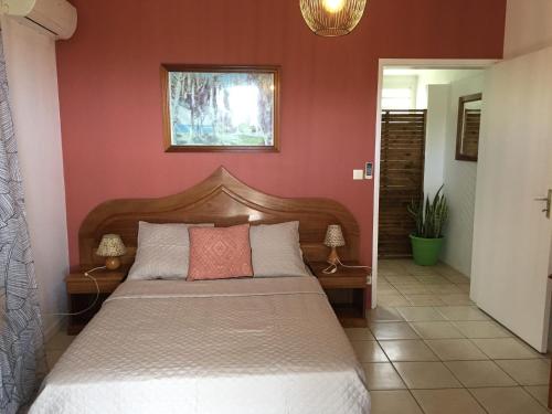 1 dormitorio con 1 cama en una pared roja en Au domaine du vacoa, en Saint-Philippe